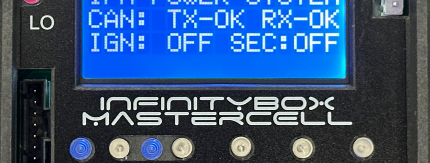 Close-up of the Infinitybox MASTERCELL NGX with the cover removed, showing the inSIGHT LCD screen displaying CAN and ignition status, CAN HI/LO indicator lights, serial number, output fuse, and menu navigation buttons.